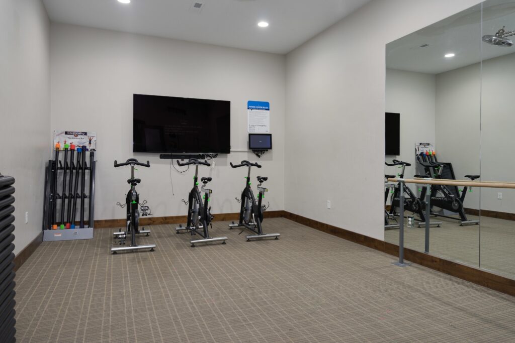 fitness center with cardio equipment and a large TV