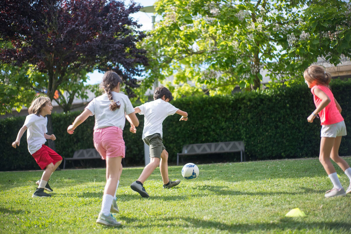 children playing in the grass with a soccer ball