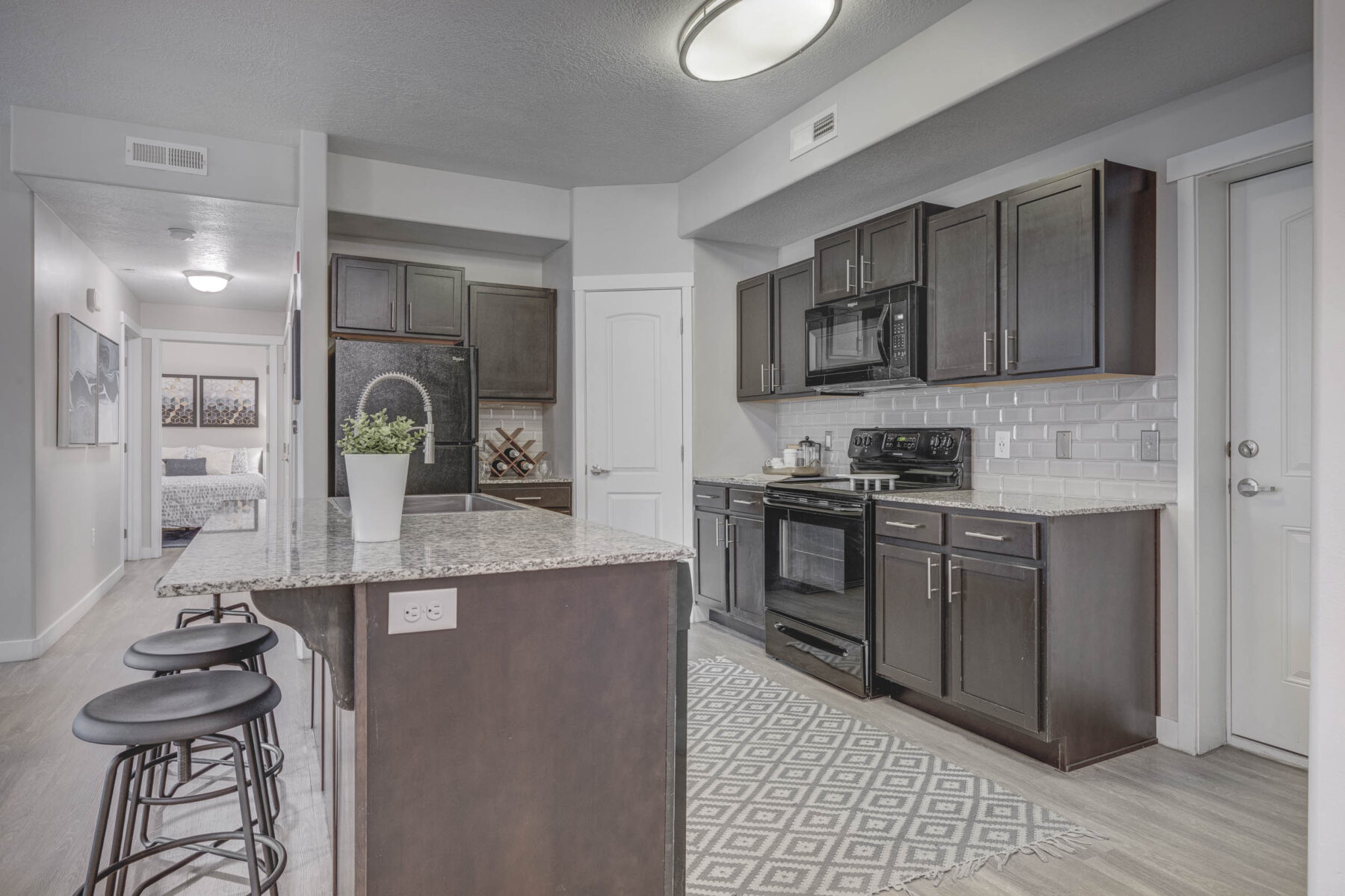 Kitchen with dark wooden cabinets, modern appliances and a kitchen island with stools